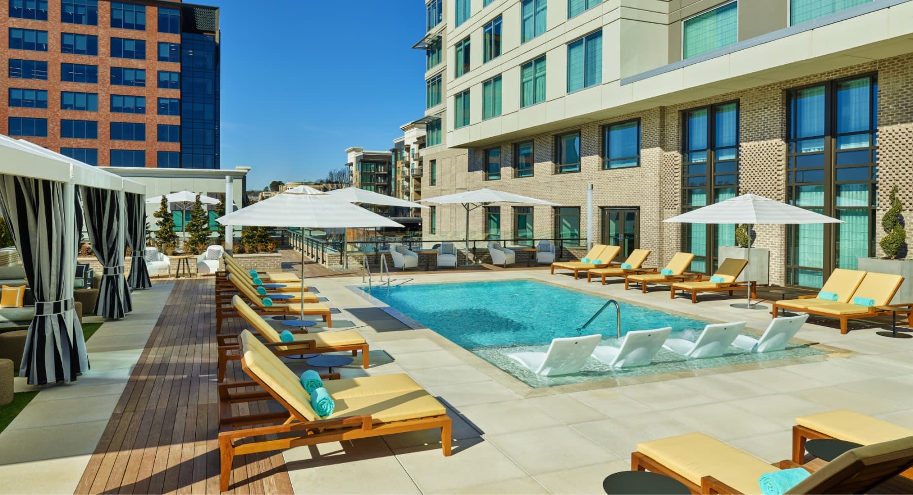 The pool terrace at The Hotel at Avalon, with lounge chairs and umbrellas beneath the hotel tower